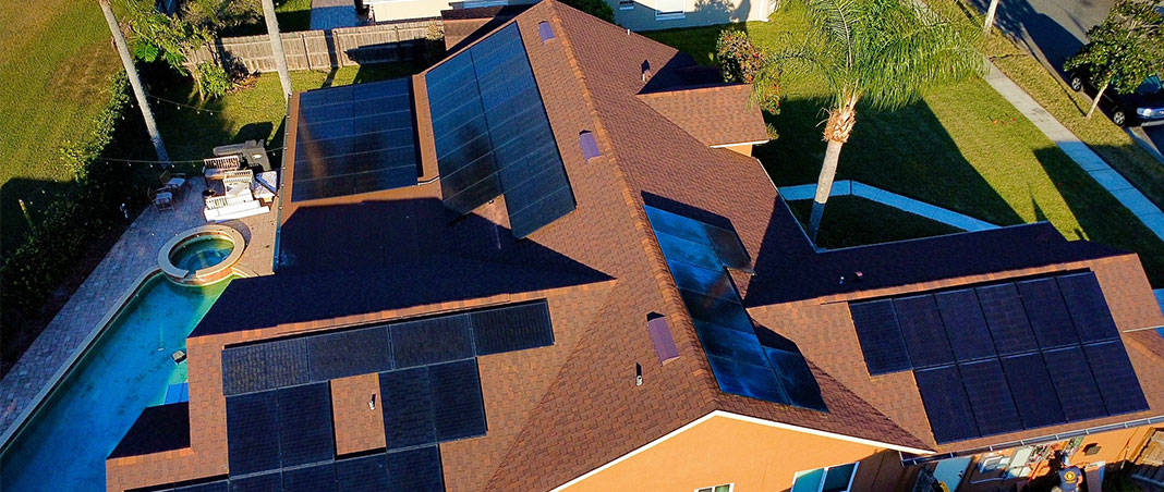Aerial view of residential rooftop solar panel installation on asphalt shingle roof with backyard pool showcasing solar roofing integration and renewable energy system by Castaways Roofing