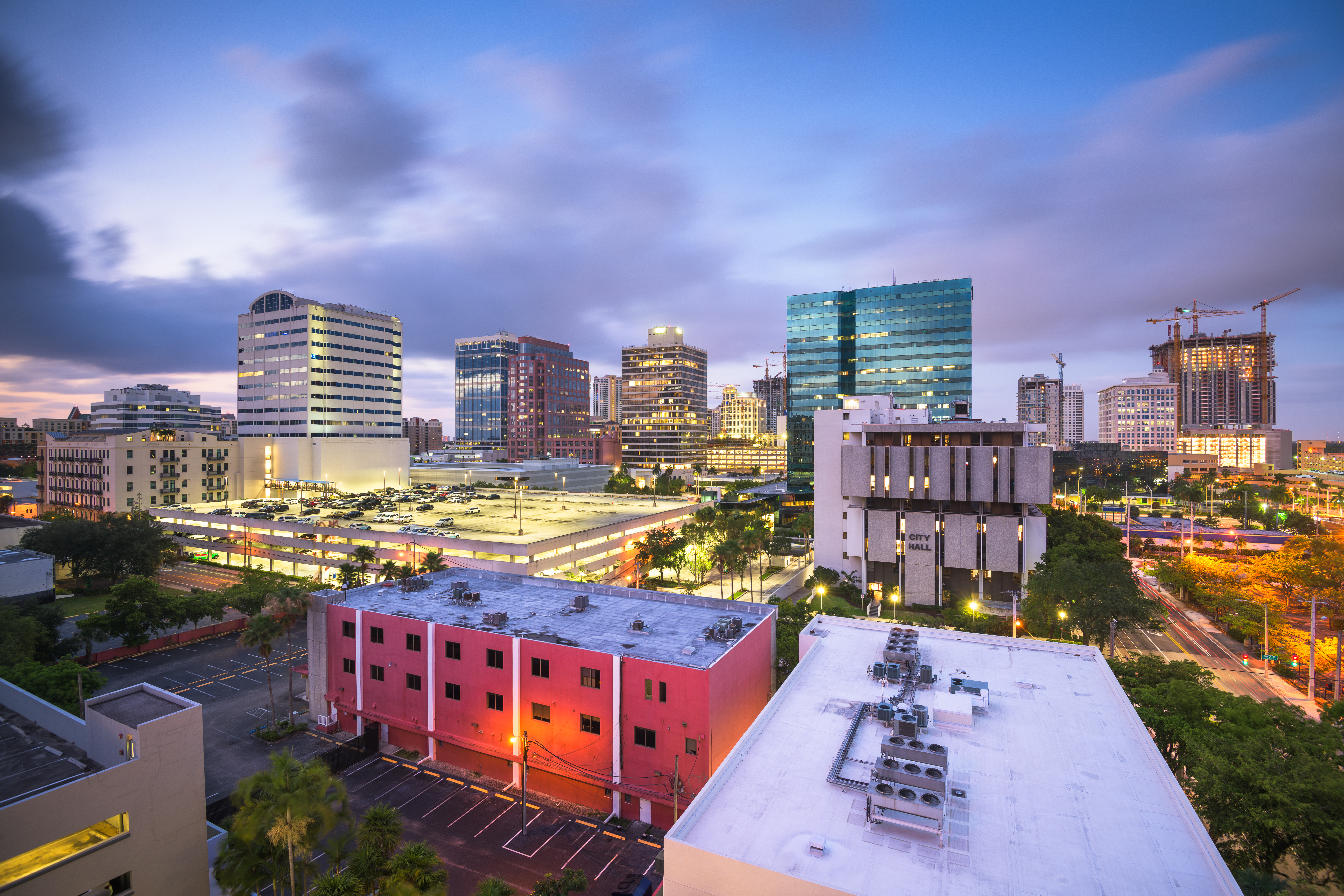 Downtown commercial buildings and flat roof systems across a modern city skyline at dusk, highlighting large-scale commercial roofing structures and urban infrastructure for Castaways Roofing services