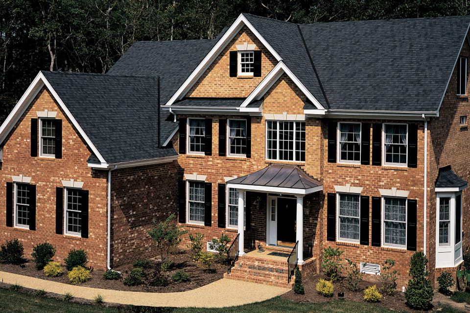 Two-story brick residential home with dark architectural asphalt shingle roof replacement showcasing professional residential roofing installation by Castaways Roofing