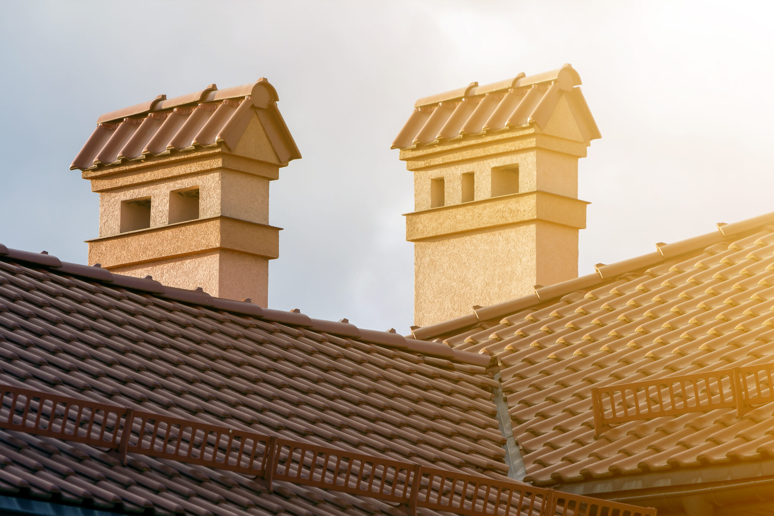 Clay tile residential roofing system with chimney stacks and roof safety guards, durable Mediterranean-style roof installation designed for long-lasting weather protection by Castaways Roofing